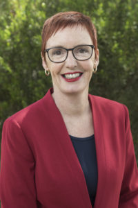 Picture of Julie Miller Markoff, Board Chair, standing in front of green foliage